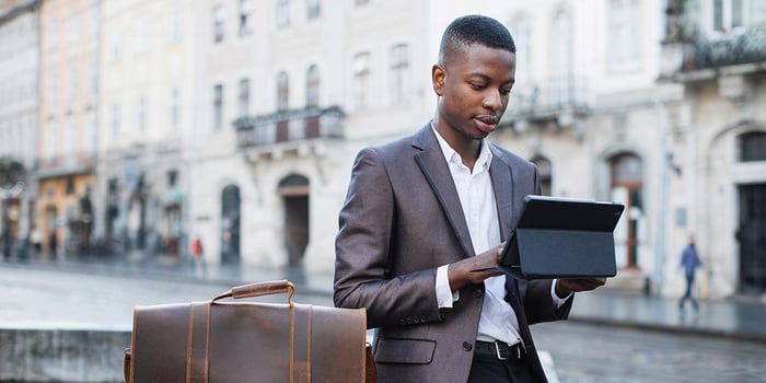 Young finance and banking professional wearing a suit using tablet outdoors